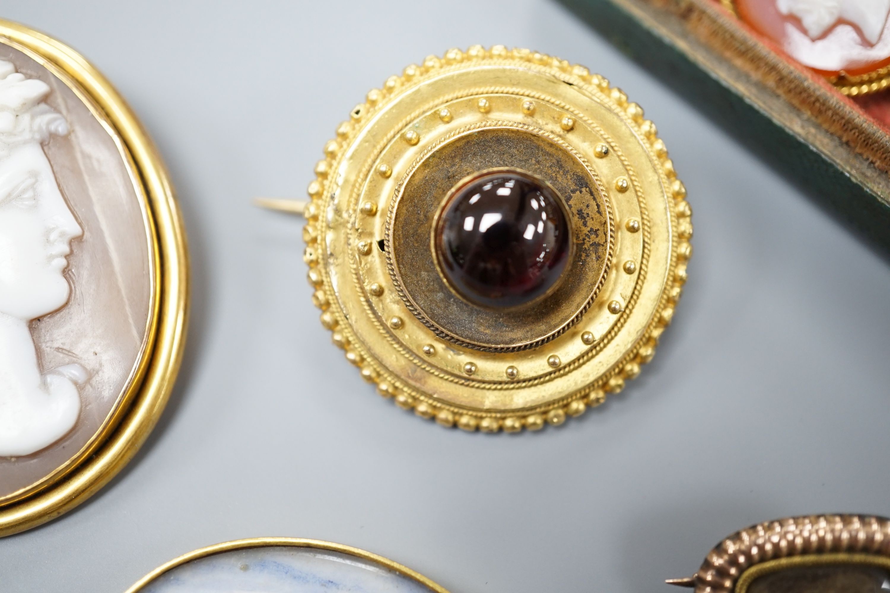 A Victorian yellow metal and cabochon garnet set circular brooch, 31mm, gross 9.3 grams, a stick pin with yellow metal and hardstone cameo set terminal, a mounted Indian miniature, a mounted cameo shell brooch and a Vict